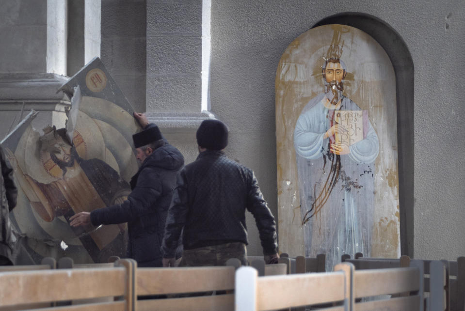 Men lift an icon in the Holy Savior Cathedral damaged by shelling during a military conflict, in Shushi, outside Stepanakert, self-proclaimed Republic of Nagorno-Karabakh, Thursday, Oct. 8, 2020. Armenia accused Azerbaijan of firing missiles into the capital of the separatist territory of Nagorno-Karabakh, while Azerbaijan said several of its towns and its second-largest city were attacked. (AP Photo)