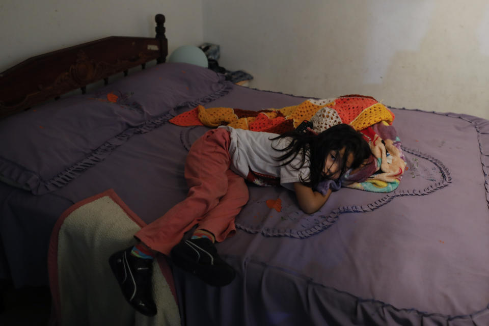 One of the four daughters of Jose Juan Serralde rests on the bed in what was her grandparent's room until both died of COVID-19, in San Gregorio Atlapulco, Xochimilco, Mexico City, Wednesday, July 29, 2020. After the grandparents died nine days apart in May, the parents and their four daughters spent weeks quarantined at home, with most of them experiencing mild cases of COVID-19 before recovering. (AP Photo/Rebecca Blackwell)