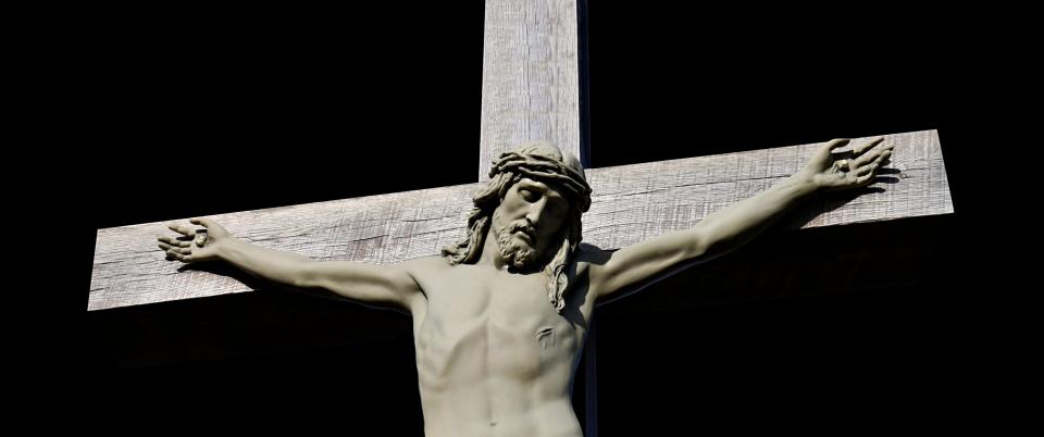 Concrete statue of crucifixion of Jesus Christ isolated on black Good Friday suffering concept