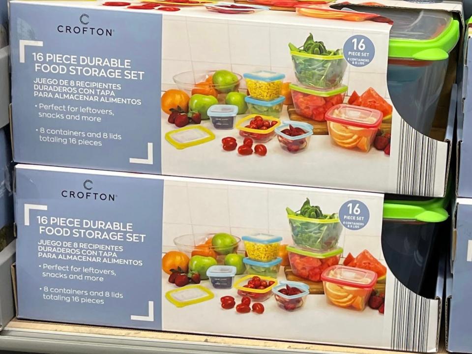 Boxes with pictures of food storage containers holding pasta, oranges, apples, spinach, and other produce. The boxes have blue labels with product details