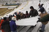 Paid volunteers prepare to clear snow at Lambeau Field in Green Bay, Wisconsin, the home field of the Green Bay Packers of the National Football League (NFL), December 21, 2013. In winter months, the team calls on the help of hundreds of citizens, who also get paid a $10 per-hour wage, to shovel snow and ice from the seating area ahead of games, local media reported. The Packers will host the Pittsburgh Steelers on Sunday, December 22. REUTERS/Mark Kauzlarich (UNITED STATES - Tags: ENVIRONMENT SPORT FOOTBALL)