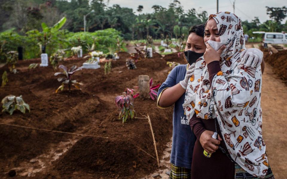  mother mourns with her son during her mother's funeral at the Mulyaharja cemetery for Covid-19 coronavirus victims, in Bogor, West Java - AFP