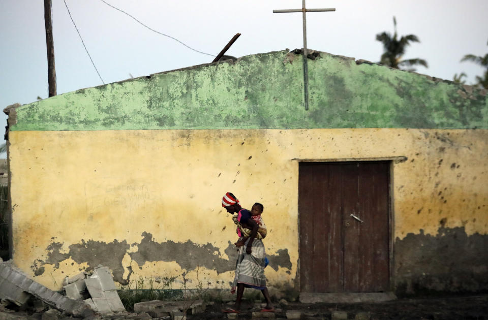 A woman carrying a baby on her back walks over a ruble of damaged houses in Beira, Mozambique, Monday, March 25, 2019. The United Nations is making an emergency appeal for $282 million for the next three months to help Mozambique start recovering from the devastation of Cyclone Idai. (AP Photo/Themba Hadebe)