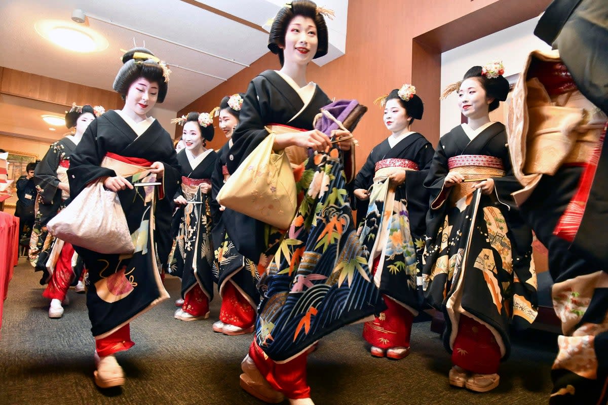 Kimono-clad "geiko" and "maiko" professional entertainers arrive for a ceremony to start this year's business in Kyoto in 2020 (AP)