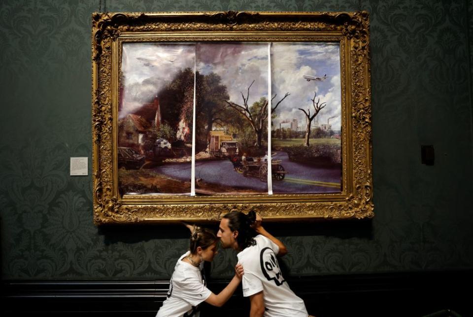 Activists from the 'Just Stop Oil' campaign group, with hands glued to the frame of the painting 'The Hay Wain' by English artist John Constable, but covered in a mock 'undated' version including roads and aircraft, protest against the use of fossil fuels, in the National Gallery in London on July 4, 2022.<span class="copyright">CARLOS JASSO/AFP—Getty Images</span>