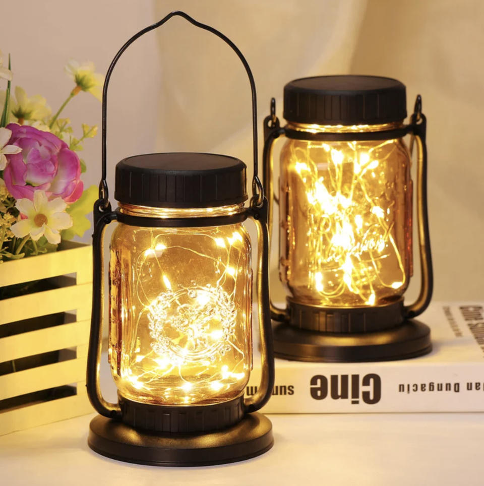 Two vintage-style mason jar lanterns with string LED lights inside, displayed on a table