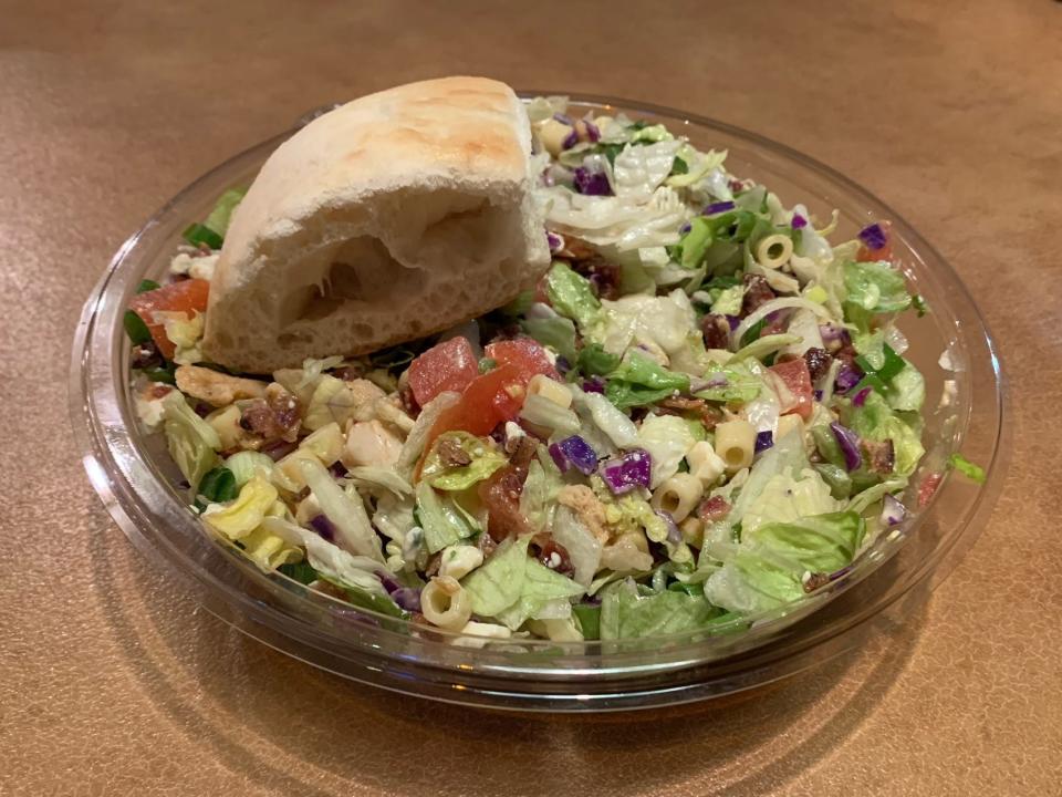 chopped salad from portillos in a plastic container with a piece of bread