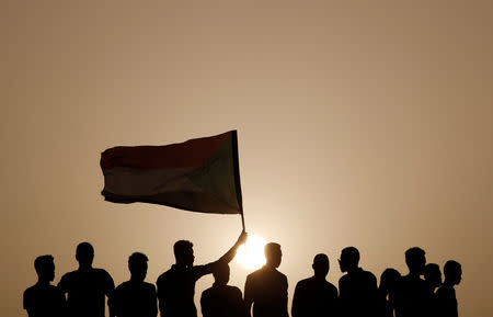 Protesters wave a Sudanese flag on top of a roof during a demonstration in front of the Defence Ministry in Khartoum, Sudan, April 18, 2019. REUTERS/Umit Bektas