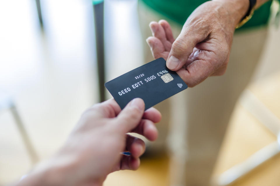 One person hands a credit card to another person's outstretched hand