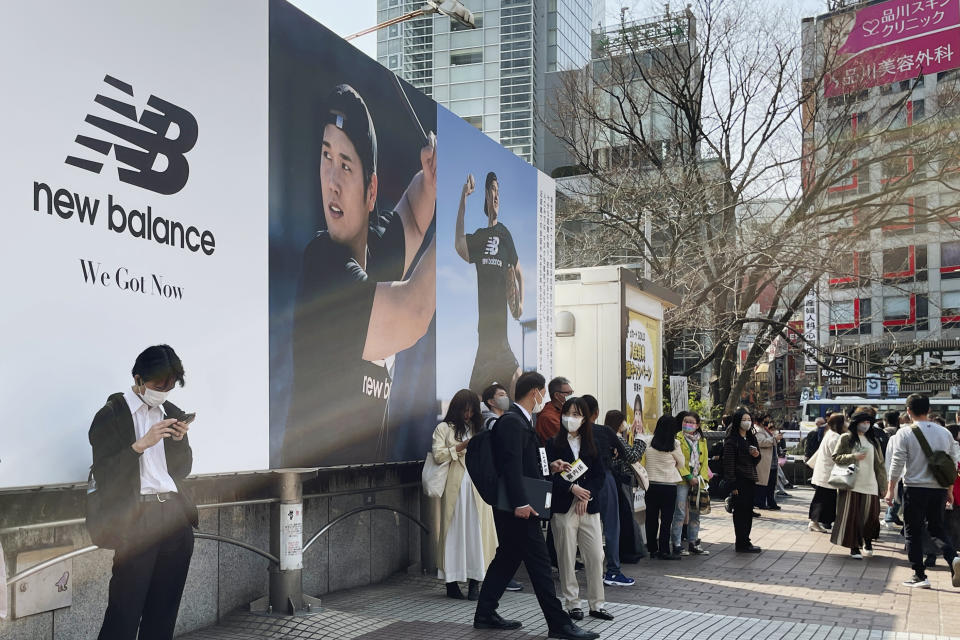 People stand by a billboard showing pictures of baseball player Shohei Ohtani installed near a train station of the famed Shibuya shopping district in Tokyo on Thursday, March 9, 2023. Japanese baseball player Shohei Ohtani is arguably the game's best player. But he's more than just a baseball player. He's an antidote for many in his native country. (AP Photo/Haruka Nuga)