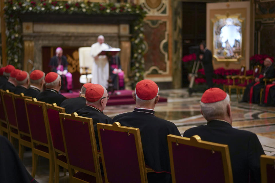 FILE - Cardinals listen as Pope Francis, background, delivers his Christmas greetings to the Roman Curia, in the Clementine Hall at the Vatican, Saturday, Dec. 21, 2019. Pope Francis has ordered pay cuts for Holy See employees, including slashing cardinals’ salaries by 10%. Francis in a letter made public by the Vatican on Wednesday, March 24, 2021, noted that the pandemic emergency “negatively impacted all sources of revenue” for the Holy See and Vatican City State. (AP Photo/Andrew Medichini, File)