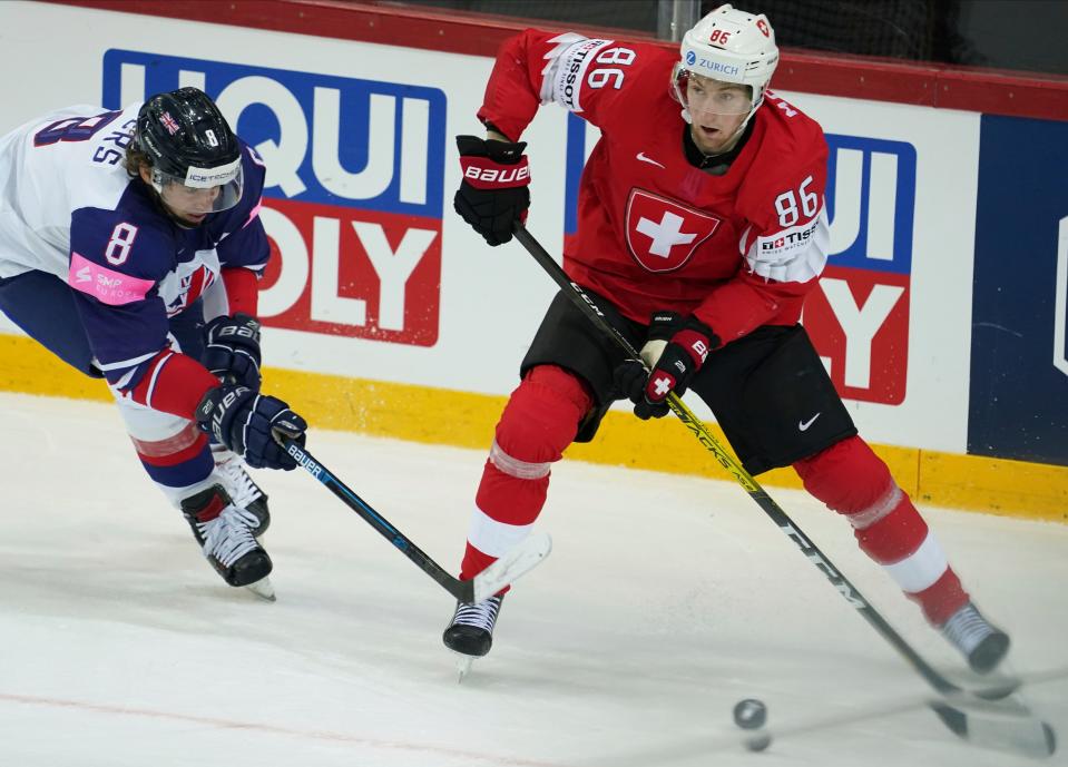 Janis Moser of Switzerland, right, fight for a puck with Matthew Myers of Britain during the Ice Hockey World Championship group A match between Switzerland and Britain at the Olympic Sports Center in Riga, Latvia, Tuesday, June 1, 2021. (AP Photo/Roman Koksarov)