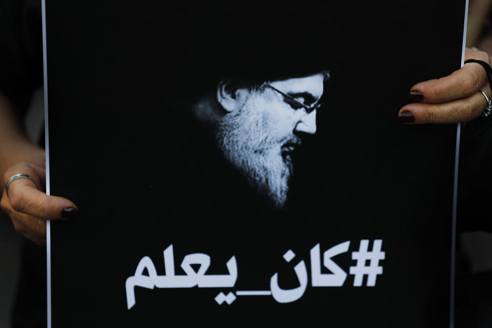 FILE – In this Oct. 6, 2021, file photo, a Lebanese protester holds a portrait of Hezbollah leader Sayyed Hassan Nasrallah with Arabic that reads, "He knew," referring to the thousand tons of ammonium nitrates that exploded last year at Beirut seaport, during a protest against the Hezbollah group and the visit of the Iranian foreign minister Hossein Amirabdollahian, in Beirut, Lebanon. Internal company documents from the former Facebook product manager-turned-whistleblower Frances Haugen show that in some of the world's most volatile regions, terrorist content and hate speech proliferate because the company remains short on moderators who speak local languages and understand cultural contexts. (AP Photo/Hussein Malla, File)