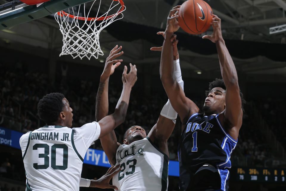 Duke's Vernon Carey Jr., right, and Michigan State's Xavier Tillman, center, and Marcus Bingham Jr., left, vie for a rebound during the first half of an NCAA college basketball game, Tuesday, Dec. 3, 2019, in East Lansing, Mich. (AP Photo/Al Goldis)