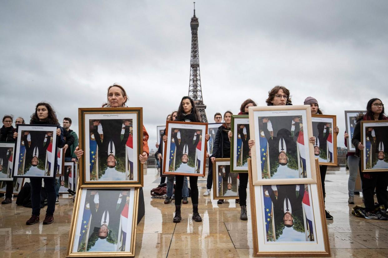 The activists held stolen portraits of the French president upside down to illustrate alleged climate hypocrisy: AFP via Getty Images