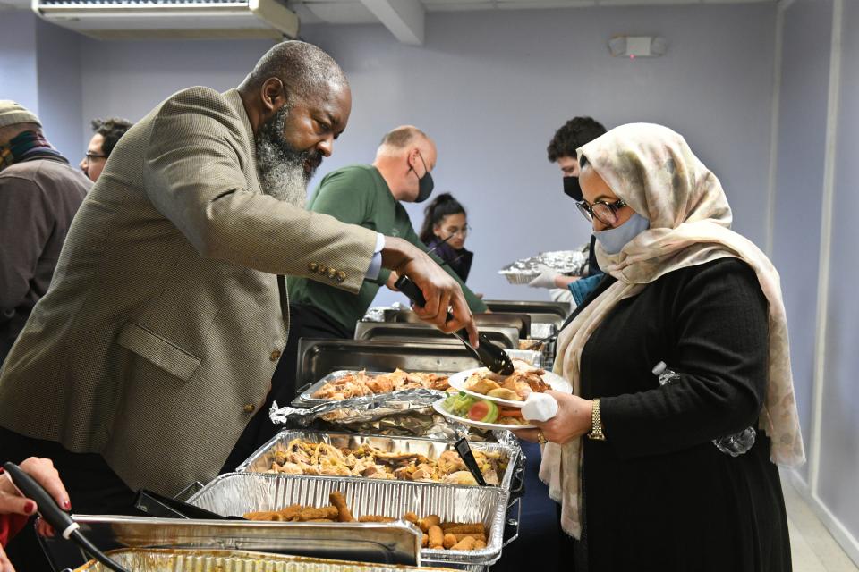 Kevin Bearden, left, volunteers at the Ethiopian Community Development Council's Thanksgiving for  Afghan, Congolese, Eritrean, Salvadoran and Ukrainian refugees on Nov. 20, 2022, in Arlington, Va.