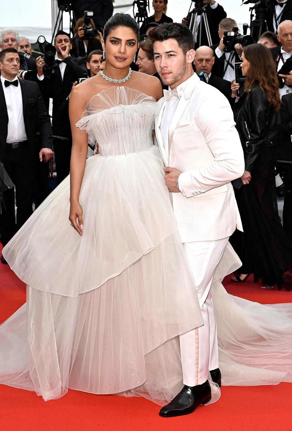 The couple pull off striking all-white ensembles while attending the premiere of <em>Les Plus Belles Annees D'Une Vie</em> on Saturday. Priyanka wears a romantic ivory tulle Georges Hobeika dress, paired with stunning jewlery from Chopard. In keeping with the monochromatic vibes, Nick wears a dapper white suit. 