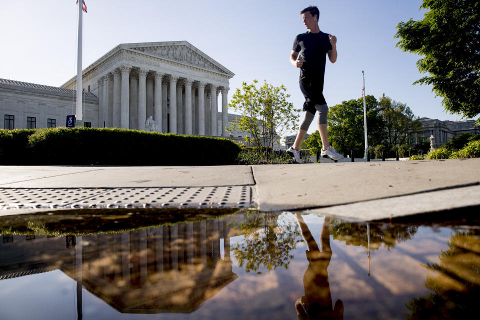 A man runs past the Supreme Court where the justices will hold arguments by telephone for the first time ever, Monday, May 4, 2020, in Washington. (AP Photo/Andrew Harnik)