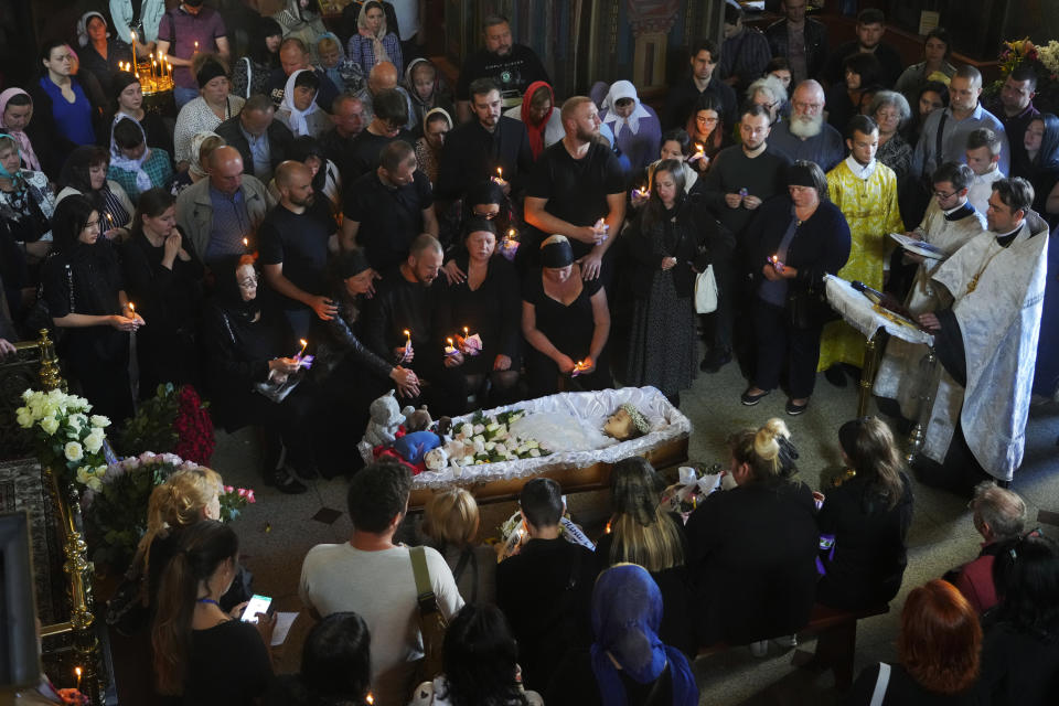 Relatives and friends pay their last respects to Liza, a 4-year-old girl killed by a Russian attack, during a mourning ceremony in an Orthodox church in Vinnytsia, Ukraine, Sunday, July 17, 2022. Wearing a blue denim jacket with flowers, Liza was among 23 people killed, including 2 boys aged 7 and 8, in Thursday's missile strike in Vinnytsia. Her mother, Iryna Dmytrieva, was among the scores injured. (AP Photo/Efrem Lukatsky)