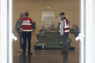 A group of officials stand in front of beds at Moscone West in San Francisco, Thursday, April 2, 2020. Since the beginning of the international pandemic, officials in California have said one population is particularly vulnerable to contracting the coronavirus and spreading it to others: the homeless. Officials are setting up 400 beds at the Moscone Center to house homeless people who are currently in shelters to allow for more social distancing. (AP Photo/Jeff Chiu)