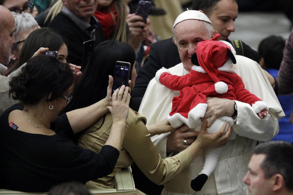 Pope Francis hugs a baby dressed as Santa Claus during audience with children and family from the dispensary of Santa Marta, a Vatican charity that offers special help to mothers and children in need, in the Paul VI hall at the Vatican, Sunday, Dec. 16, 2018. (AP Photo/Gregorio Borgia)