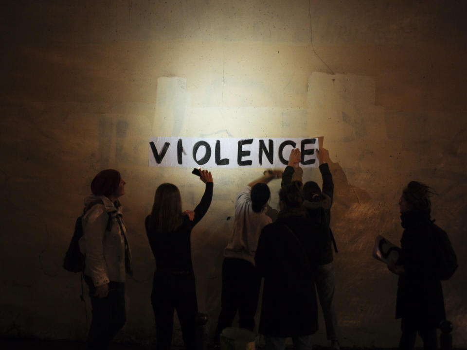 In this Oct. 31, 2019 photo, the word "violence" is pasted onto a wall by a group of women in a dark street in Paris. In Paris and cities across France, the signs are everywhere. "Complaints ignored, women killed" and "She leaves him, he kills her," they read in black block letters pasted over stately municipal buildings. Under cover of night, activists have glued them to the walls to draw attention to domestic violence, a problem French President Emmanuel Macron has called "France's shame." (AP Photo/Kamil Zihnioglu)