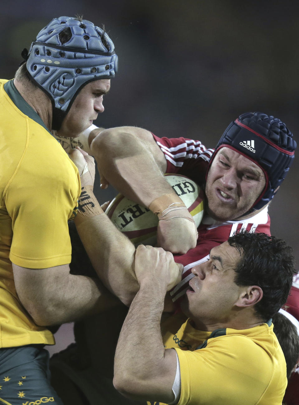 FILE - British and Irish Lions' Sean O'Brien, center, charges through Australia's James Horwill, left, and George Smith during their rugby union test match in Sydney, Australia, on July 6, 2013. The Rugby World Cup will take place to the backdrop of a concussion lawsuit that has similarities to one settled by the NFL in 2013 at a likely cost of more than $1 billion. (AP Photo/Rick Rycroft, File)