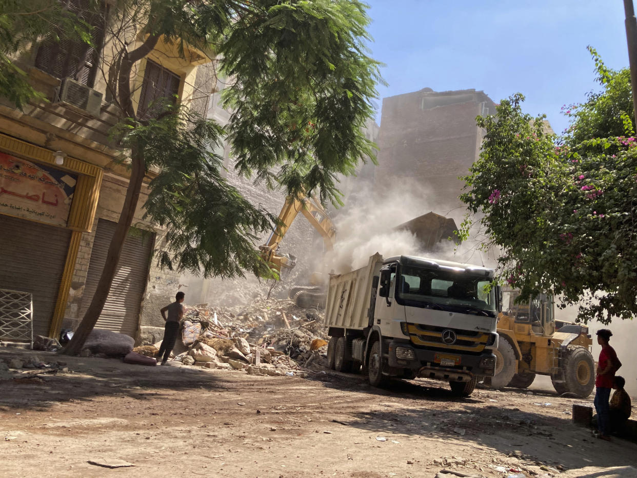 Residents and rescue workers sift through the rubble of a collapsed building in El-Weili neighborhood, Cairo, Egypt, Friday, June 17, 2022. A five-story apartment building collapsed in the Egyptian capital early Friday, killing numerous people according to officials. (AP Photo/Ahmed Hatem)