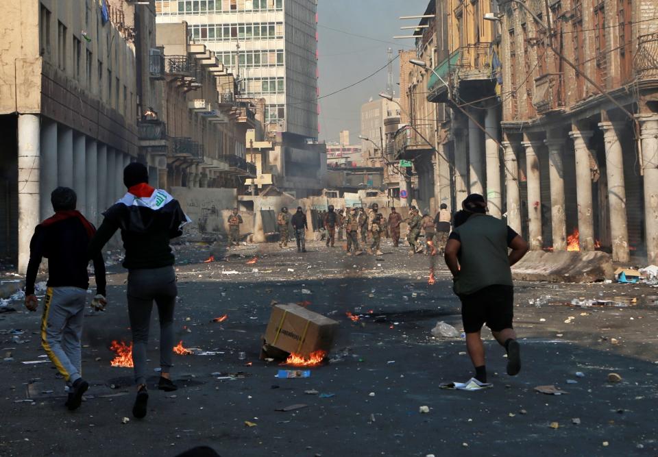 Anti-government protesters throw Molotov cocktails toward riot police during clashes with security forces in Baghdad, Iraq, Tuesday, Nov. 26, 2019. (AP Photo/Khalid Mohammed)