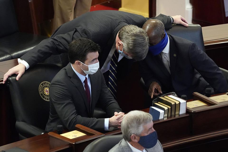 FILE - In this Jan. 13, 2021 file photo, Sen. Mike Woodard, D-Durham, speaks with Sen. Ben Clark, D-Hoke, right, and Sen. Jeff Jackson, D-Mecklenburg in the Senate chamber during the opening session of the North Carolina General Assembly in Raleigh, N.C.    Jackson has announced he’s running for the U.S. Senate in 2022.  Jackson unveiled his bid on Tuesday, Jan, 26, 2021. He's the second Democrat to enter the race to succeed Republican Sen. Richard Burr, who isn’t seeking reelection.(AP Photo/Gerry Broome, File)