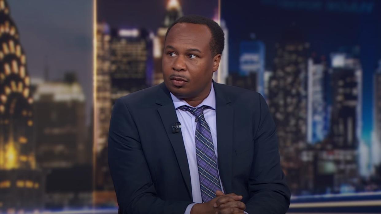  Roy Wood Jr. sitting at the main desk on The Daily Show. 