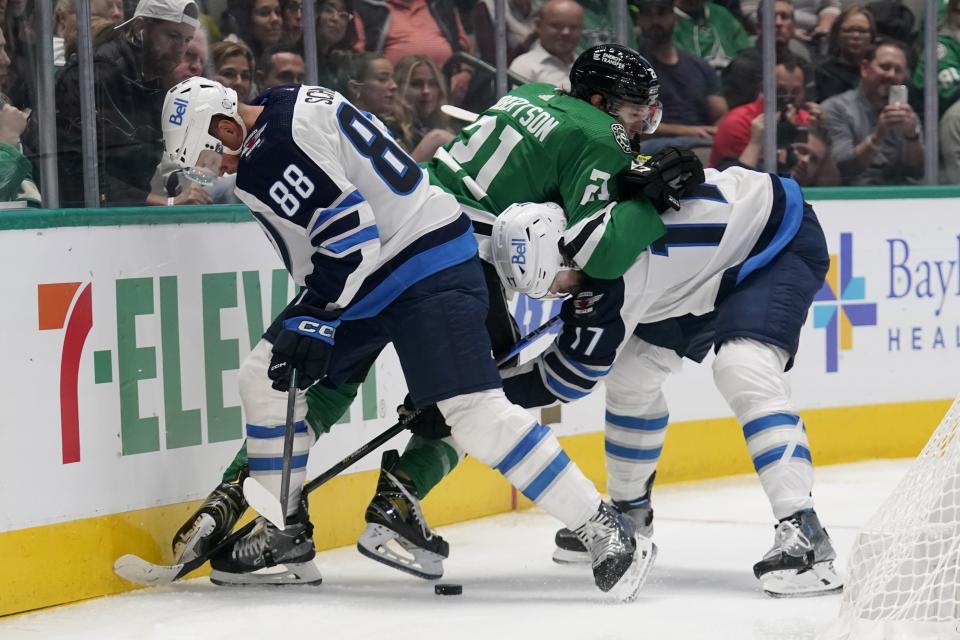 Winnipeg Jets' Nate Schmidt (88) and Adam Lowry (17) work to take control of the puck under pressure from Dallas Stars left wing Jason Robertson (21) in the first period of a NHL hockey game in Dallas, Monday, Oct. 17, 2022. (AP Photo/Tony Gutierrez)