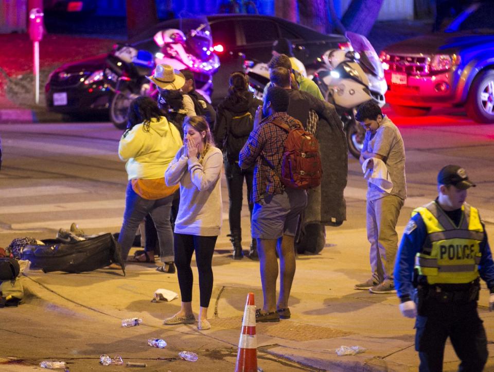 Bystanders react after several people were struck by a vehicle on Red River Street in downtown Austin, Texas, at SXSW on Wednesday March 12, 2014. Police say two people were confirmed dead at the scene after a car drove through temporary barricades set up for the South By Southwest festival and struck a crowd of pedestrians. (AP Photo/Austin American-Statesman, Jay Janner)