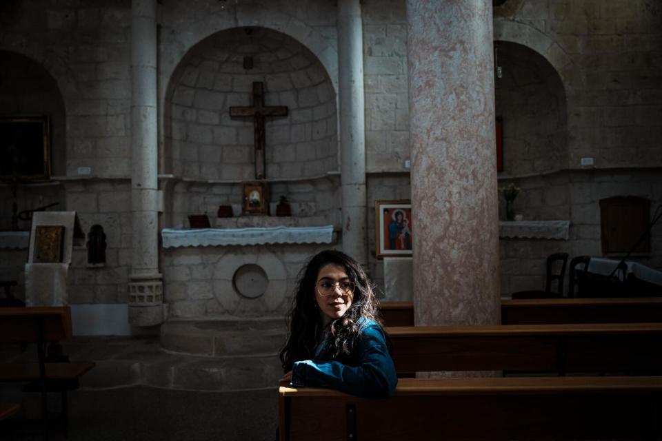 Maryam Younnes sits in the beam of light shining into an ancient Maronite Church