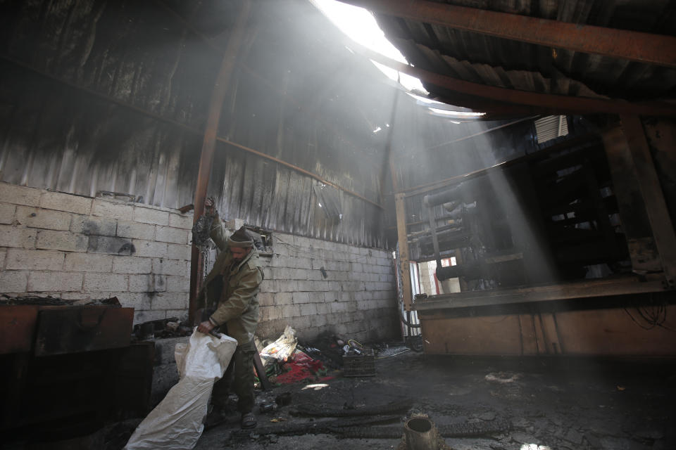 A worker inspects the damage to plastic materials factory destroyed by Saudi-led airstrikes, in Sanaa, Yemen, Tuesday, Nov. 23, 2021. (AP Photo/Hani Mohammed)