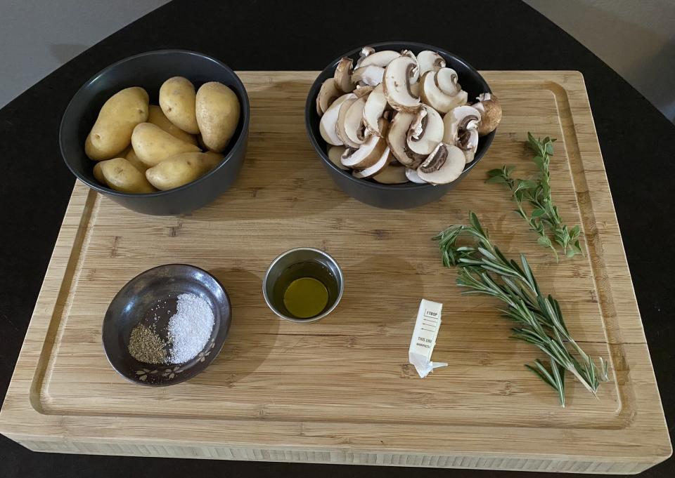 potatoes, mushrooms, seasonings, oil, butter, and herbs on a wooden cutting board