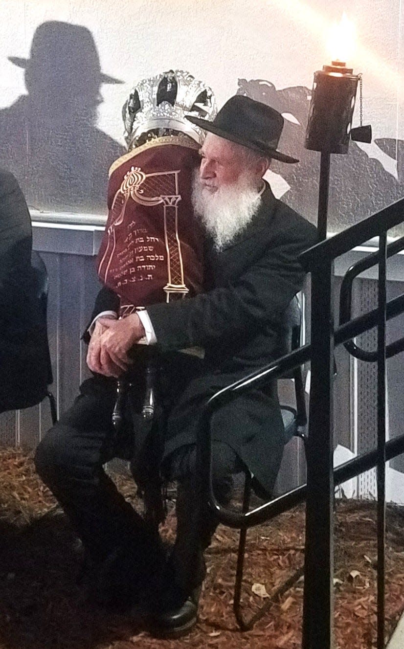 Eliezer Reinhold, the Rabbi Schneur Oirechman's father-in-law, holds the new Torah on Tuesday, Oct. 10, 2023.