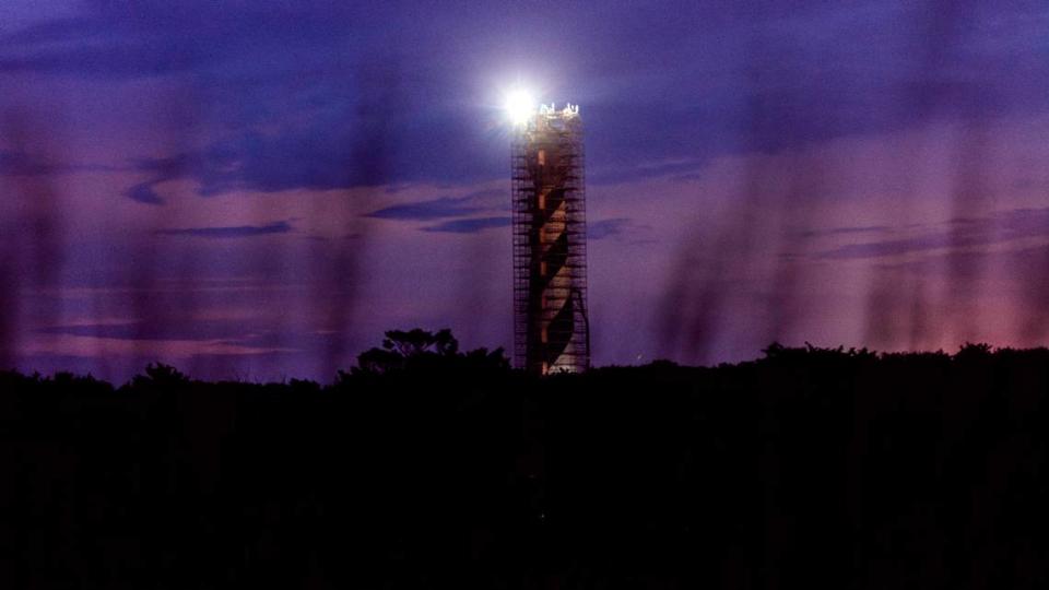 The Cape Hatteras Lighthouse is surrounded by scaffolding against the night sky as it undergoes restoration on Sunday, June 30, 2024. The project is expected to cost $19.2 million and will include replacing 40,000 of its estimated 1,250,000 bricks, replacing rusted or broken metal components and the installation of a near-exact replica of the first-order Fresnel lens.