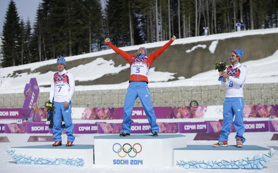 Russia's gold medal winner Alexander Legkov is flanked by Russia's silver medal winner Maxim Vylegzhanin, left and Russia's bronze medal winner Ilia Chernousov during the flower ceremony of the men's 50K cross-country race at the 2014 Winter Olympics, Sunday, Feb. 23, 2014, in Krasnaya Polyana, Russia. (AP Photo/Gregorio Borgia)