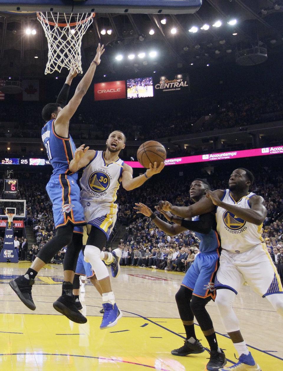 Golden State Warriors' Stephen Curry (30) drives to the basket as Oklahoma City Thunder's Andre Roberson, left, defends next to Thunder's Victor Oladipo, second from right, and Warriors' Draymond Green, right, during the first half of an NBA basketball game Wednesday, Jan. 18, 2017, in Oakland, Calif. (AP Photo/Marcio Jose Sanchez)