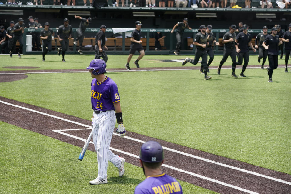 East Carolina's Ben Newton (24) walks to the dugout as Vanderbilt players celebrate after Newton lined out to end their NCAA college baseball super regional game Friday, June 11, 2021, in Nashville, Tenn. Vanderbilt won 2-0. (AP Photo/Mark Humphrey)