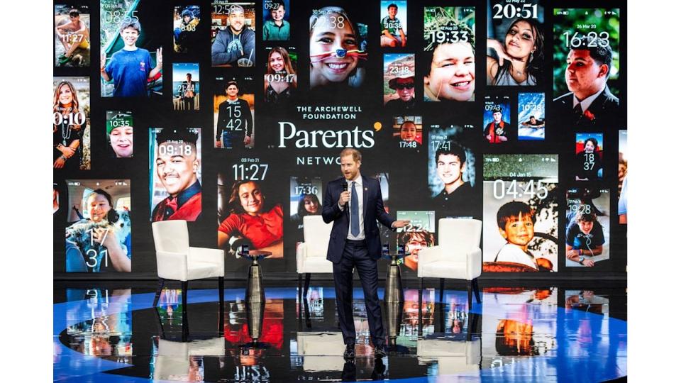 Prince Harry on stage in front of images of phone lockscreens