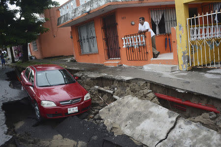 A man stands near a car after heavy rains damaged a street in Veracruz September 2, 2014. REUTERS/Jonatan Rosas