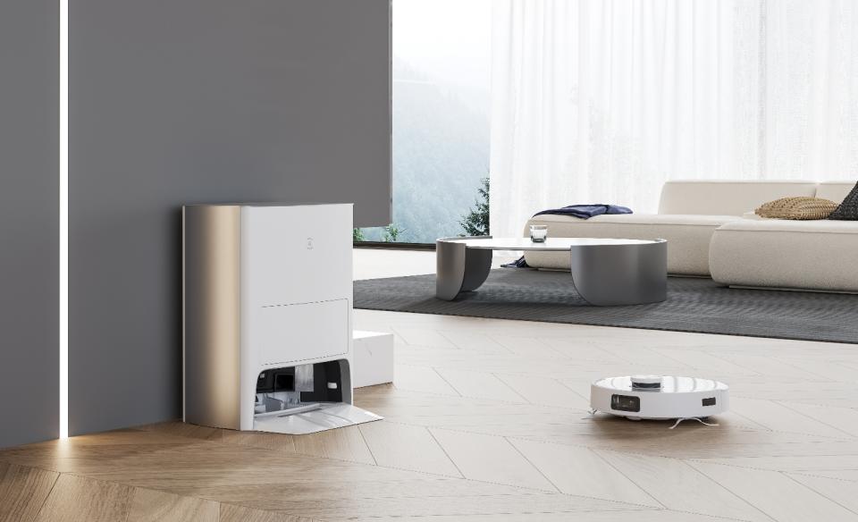 A robot vacuum approaching its tall charging / cleaning station in a modern living room.