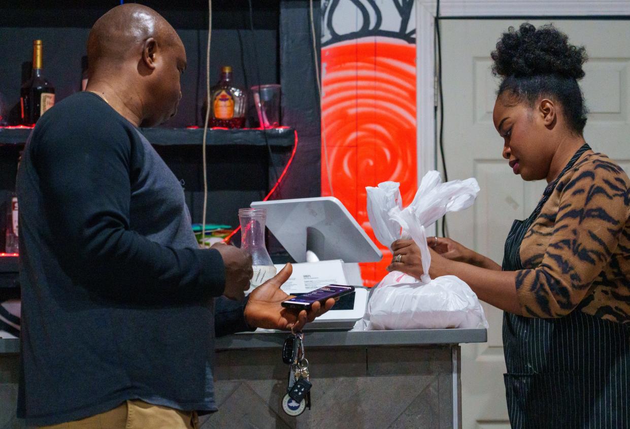 Sarah Awodumila fulfills an online order Friday, Feb. 23, 2024, inside Jollof Buka, her restaurant at the corner of West Washington and Belleview Place. Awodumila says the majority of her food business are to-go delivery orders, something she hopes changes with the potential of more foot traffic.