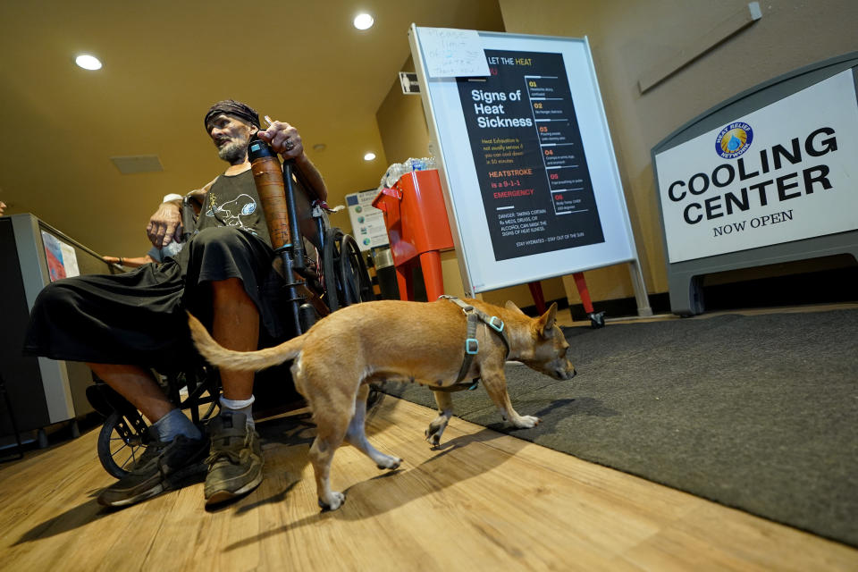 FILE - Charles Sanders, 59, and his dog Babygirl, cool off inside the Justa Center, July 14, 2023, in downtown Phoenix. Homeless people are among the people most likely to die in the extreme heat in Phoenix. The city is seeing its longest run of consecutive days of 110 degree Fahrenheit (43 degrees Celsius) ever recorded. (AP Photo/Matt York, File)