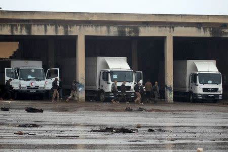 Rebel fighters walk near Red Crescent vehicles on their way to al Foua and Kefraya, in Idlib province, Syria January 11, 2016. REUTERS/Ammar Abdullah