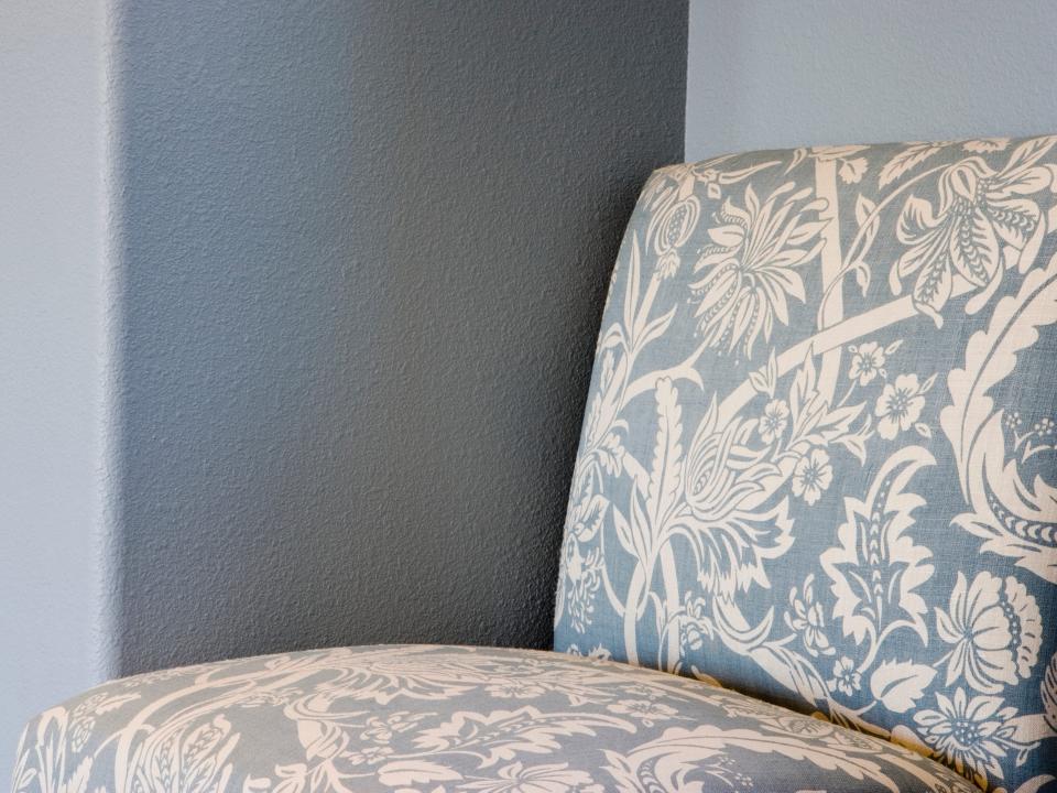 Blue and white upholstered chair in front of gray wall