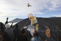 A worshipper throws chicken into the crater of Mount Bromo as an offering to the gods during Yadnya Kasada festival in Probolinggo, East Java, Indonesia, Saturday, June 26, 2021. Every year people gather for the annual festival where offerings of rice, fruit, vegetables, livestock or money are made to Hindu gods at the active volcano to ask for blessings and assure a bountiful harvest. (AP Photo/Trisnadi)