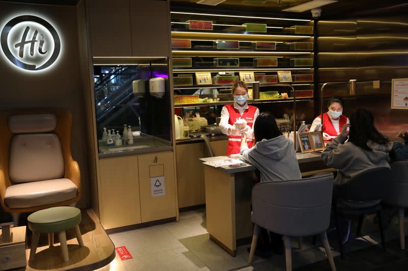 Manicurists take care of hands of customers at a manicure section of a Haidilao hotpot restaurant, in Beijing